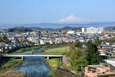 秋田県横手市を流れる小川と橋と市街地の街並み