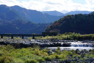 鳥取県八頭町を流れる川とその上を走る電車の町並み